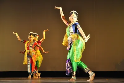 Three dancers in colorful Indian costumes performing to Rabindra Sangeet on a Kolkata stage