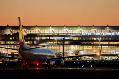 Airliner taxiing in front of the illuminated Tokyo International Airport terminal at dusk