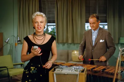 Peggy Lee singing into a handheld microphone as Sonny Burke plays vibraphone, 1950s color photo
