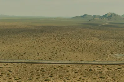 Film still from Sicario: wide aerial view of desert, a border fence and rocky mountains