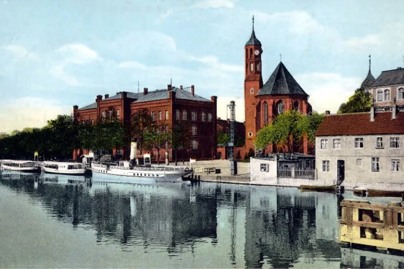 Vintage tinted postcard of Brandenburg an der Havel with a brick church tower and riverboats