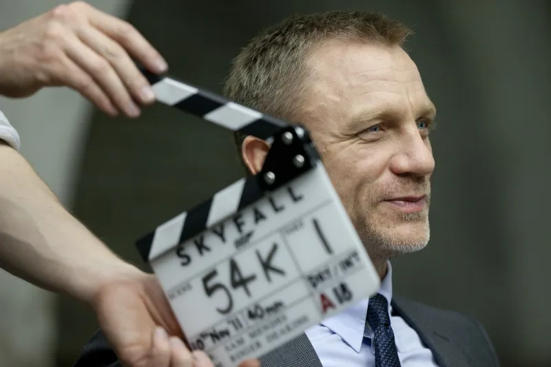 Skyfall film clapperboard held up in front of a smiling actor in suit and tie