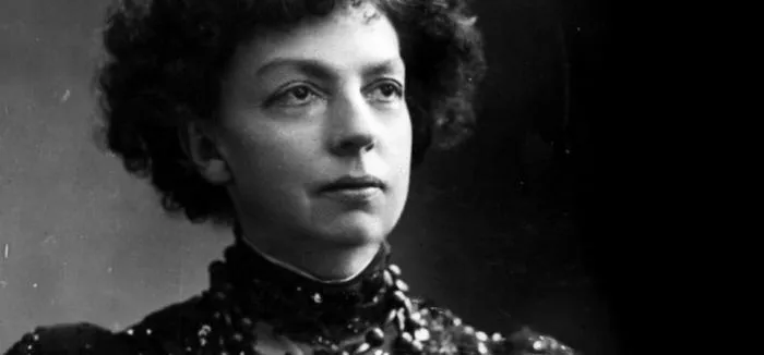 Black-and-white portrait of Cécile Chaminade with curly hair and a beaded high collar