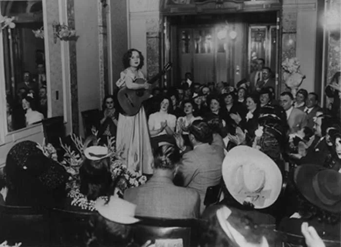 Young María Luisa Anido performing guitar for an applauding audience at Salón La Argentina