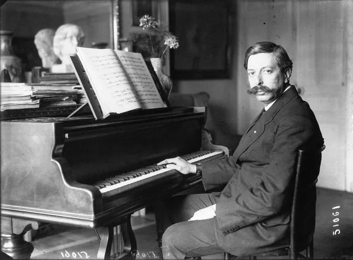 Black-and-white photo of Enrique Granados seated at a grand piano with open sheet music