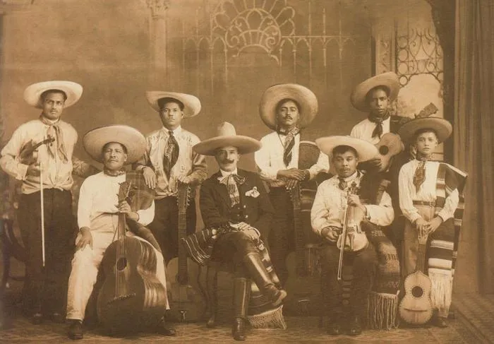 Sepia group portrait of an early mariachi band in sombreros with violins and guitars