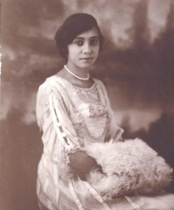 Sepia studio portrait of a young Florence Price in a lace dress, pearls and fur muff