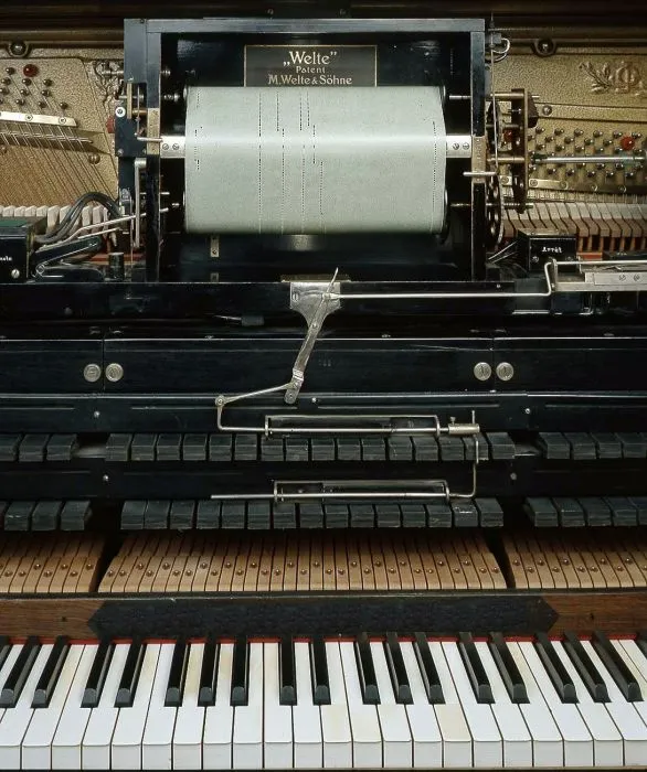 Welte reproducing piano mechanism with a perforated paper roll mounted above the keyboard