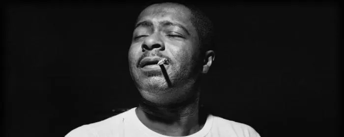 Black-and-white portrait of jazz pianist Wynton Kelly, eyes closed, cigarette in his mouth